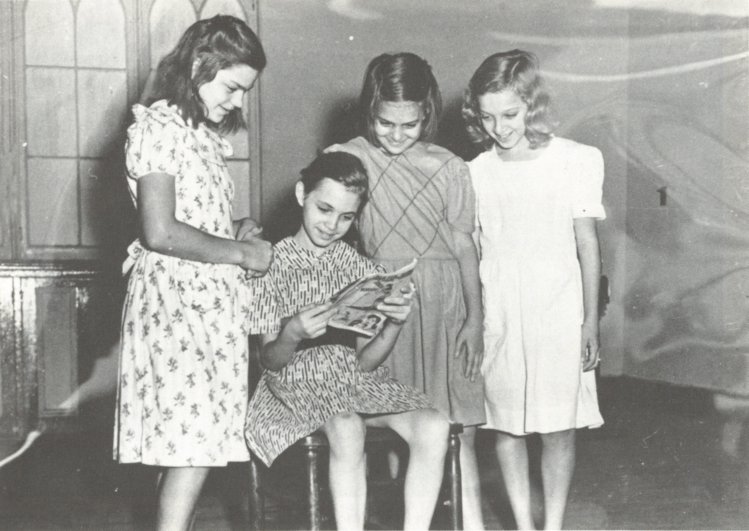 Old picture of younf girls standing and reading a book