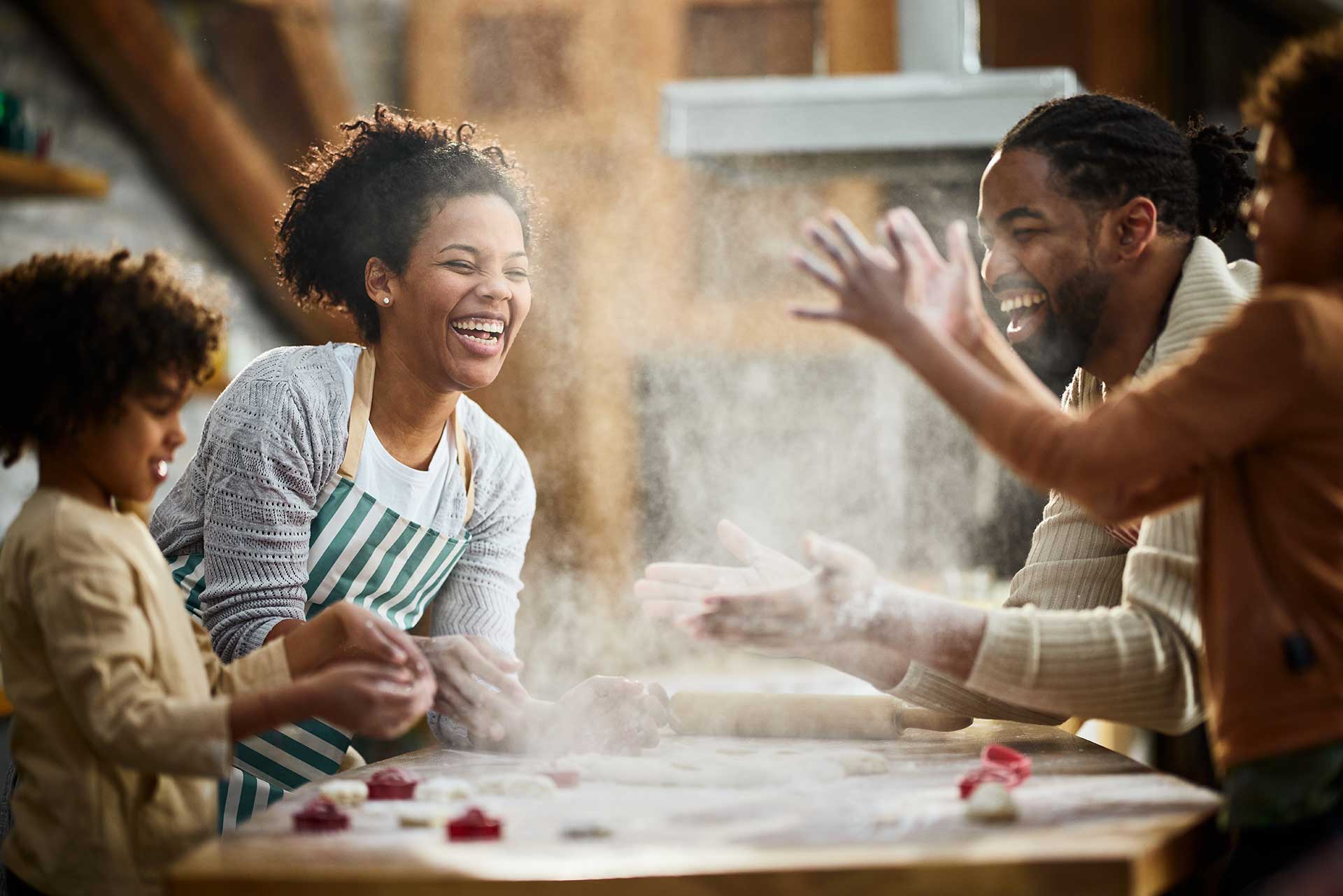 Cheerful black family having fun with flour in the kitchen