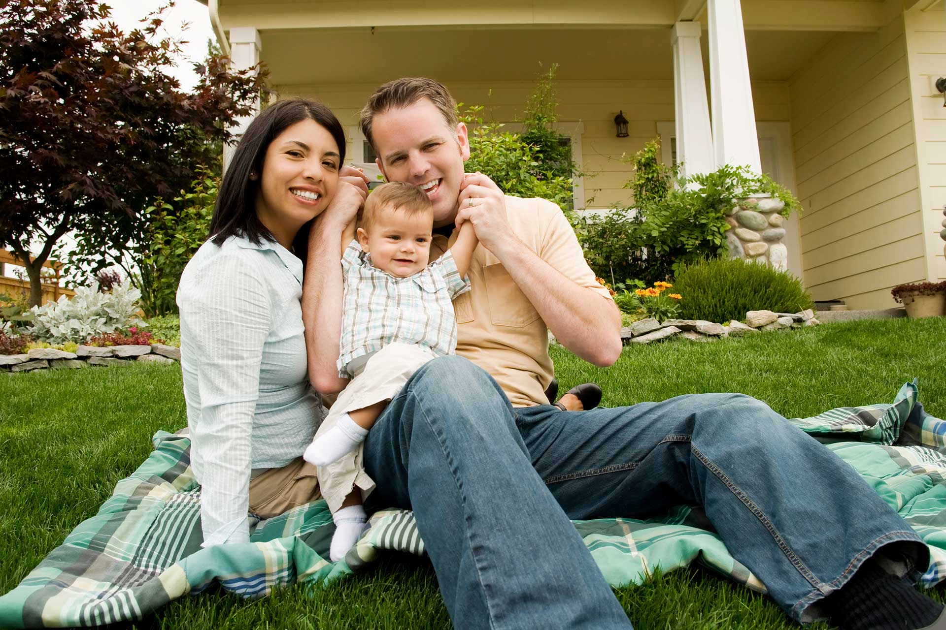 Happy Family Sitting outside their house on the grass