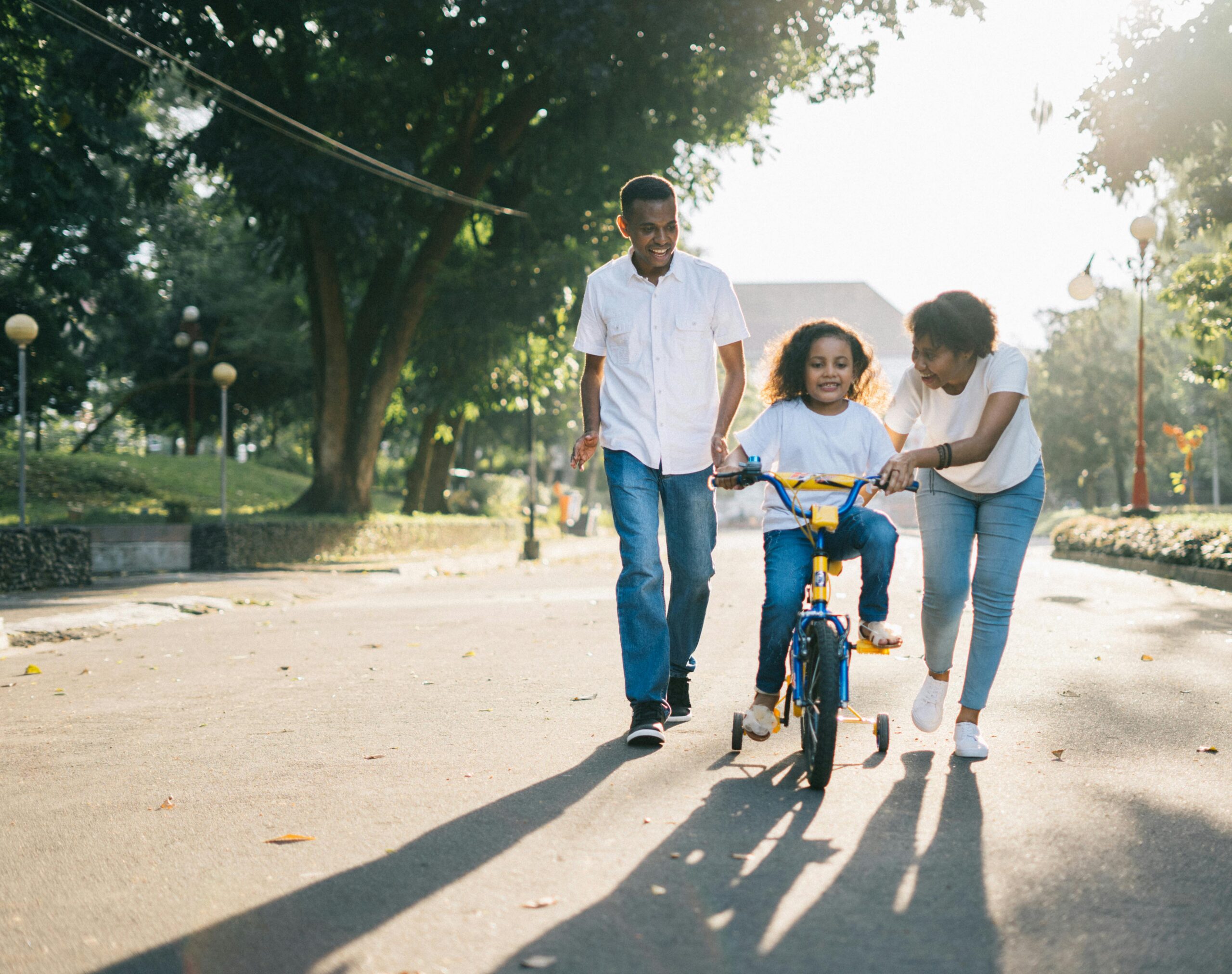 Family teaching child to ride a bike